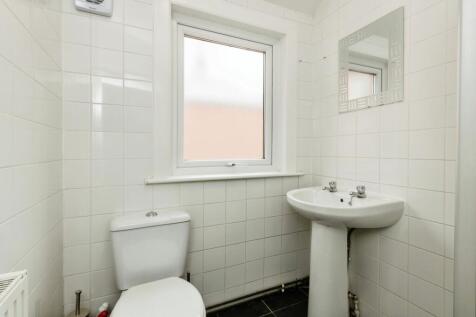 A clean bathroom featuring a compact washbasin,...
