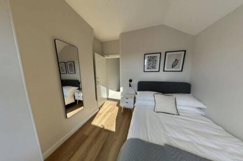 A bright, modern double bedroom with a comforta...