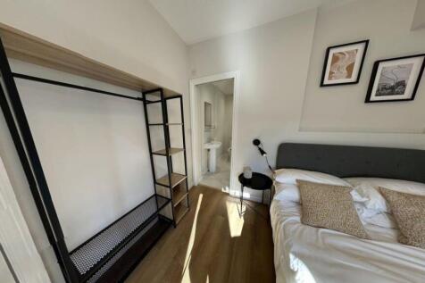 A well-lit bedroom featuring a neatly made bed ...