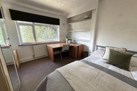 A cozy student bedroom featuring a neatly made ...