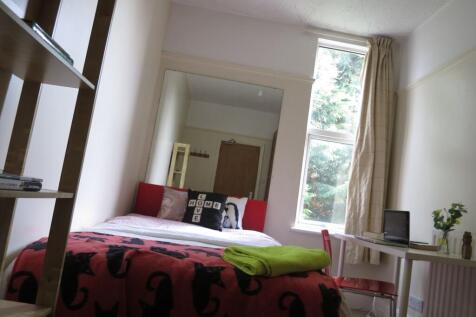 A well-lit bedroom featuring a large bed with v...