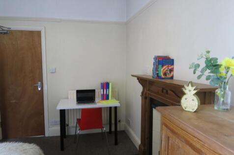 A cozy bedroom featuring a small desk with a la...