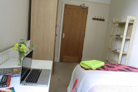 A cozy student bedroom featuring a neatly made ...