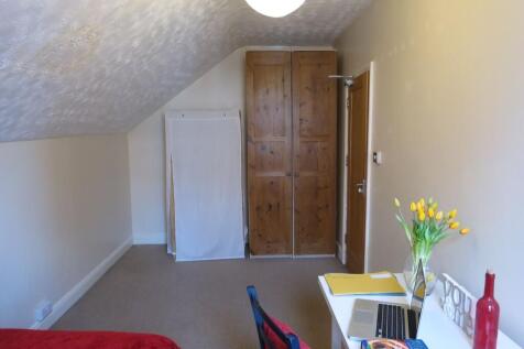 A cozy bedroom featuring a sloped ceiling, a wa...