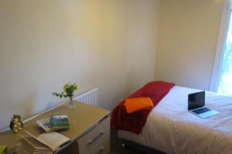 A cozy single bedroom featuring a neatly made b...