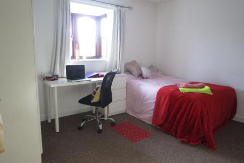 A cozy single bedroom featuring a bed with pink...