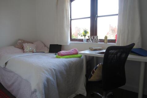 A cozy bedroom featuring a neatly made bed with...