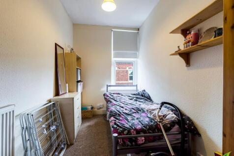 A compact single bedroom with a small bed, stra...