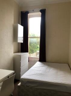 A tidy double bedroom with a bed and a desk, fe...