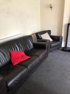 A tidy but dimly lit living room with a brown l...