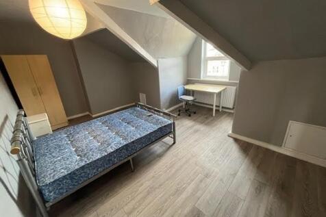 A bright and tidy bedroom with sloped ceilings,...