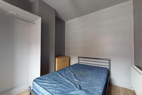 A tidy bedroom featuring a simple bed frame wit...