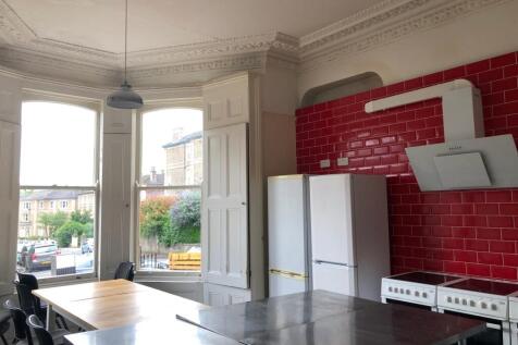 A spacious kitchen with red tiled walls, large ...