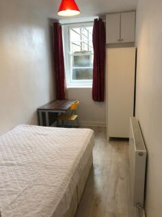 A tidy double bedroom featuring a bed, desk, an...