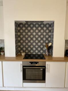 Stylish kitchen alcove with patterned tile spla...
