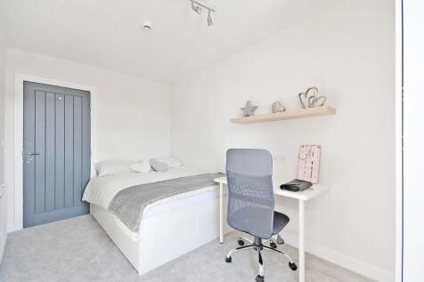 A bright and clean single bedroom featuring a c...