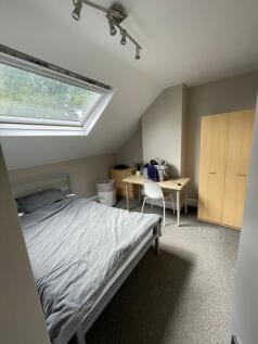 A cozy bedroom featuring a double bed, a desk, ...