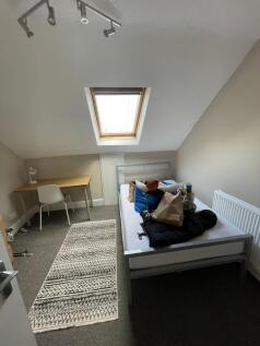 A cozy single bedroom featuring a sloped ceilin...