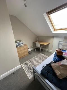 A cozy student bedroom featuring a single bed, ...