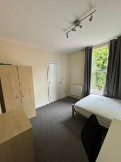 A bright and tidy bedroom featuring a window wi...