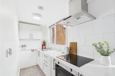 Bright, modern galley kitchen with white cabine...