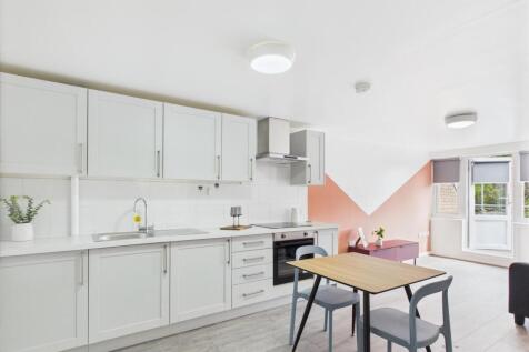 Bright open-plan kitchen with white fitted cabi...