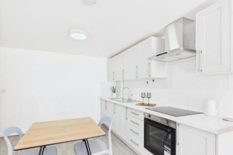 Bright modern kitchen with white cabinetry, int...