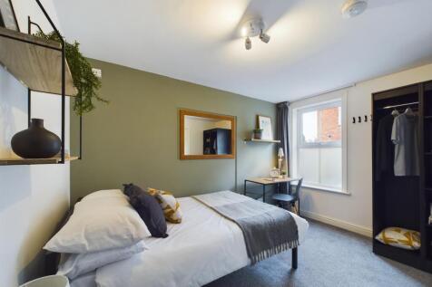 A bright and welcoming bedroom featuring a comf...