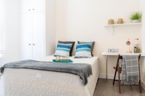 Bright, neatly styled bedroom with a comfortabl...