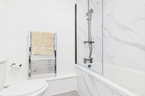 Bright, modern bathroom featuring a white bath ...