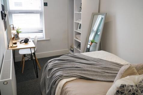 A bright and cozy bedroom featuring a neatly ma...