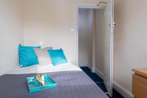 Bright, simply styled bedroom with a neatly mad...