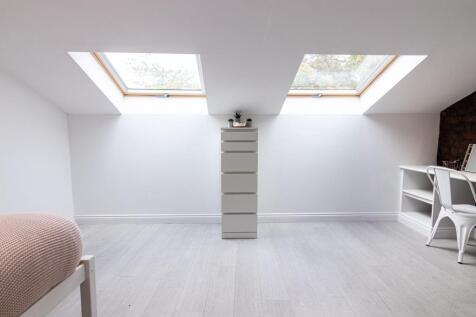 Bright, modern attic bedroom with two large sky...