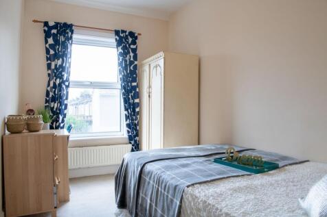 Bright, neatly styled bedroom with a large wind...