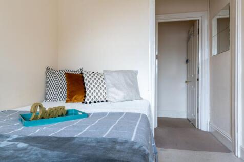 Bright, neatly styled bedroom with a made bed, ...