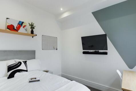 A bright and modern double bedroom featuring st...