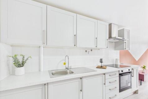 Bright modern kitchen with white cabinetry, int...