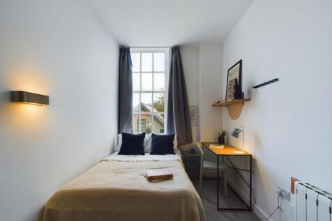 A bright and tidy single bedroom featuring a co...