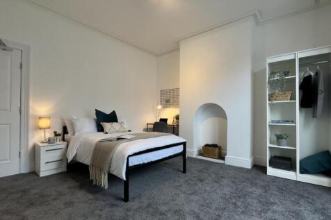 A spacious and inviting double bedroom with gre...