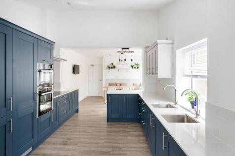 Bright, modern galley kitchen with deep blue sh...