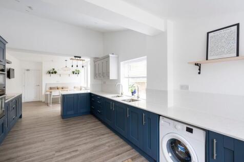 Bright, modern kitchen with deep blue shaker-st...