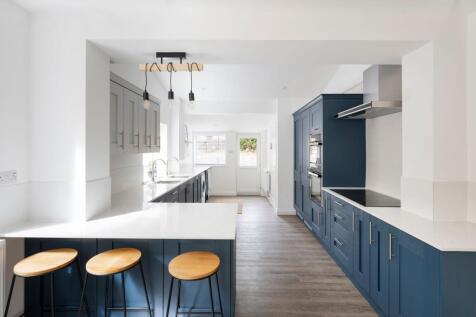 Bright modern kitchen with deep blue cabinetry,...