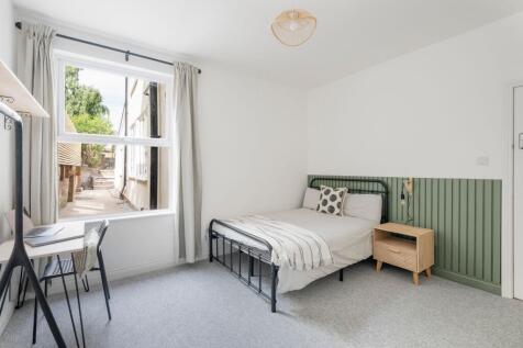 Bright, neatly styled bedroom with a metal doub...