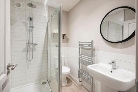 Bright, modern bathroom with a glass shower enc...