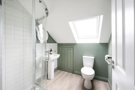 Bright, modern attic bathroom with a corner gla...