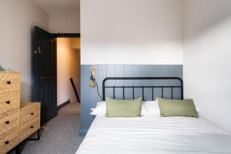 Bright, neatly styled bedroom with a metal bedf...