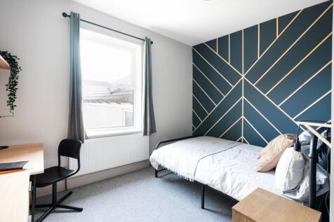 Bright, neatly styled bedroom with a bold geome...