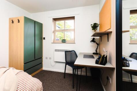 Bright, neatly presented bedroom with a study d...