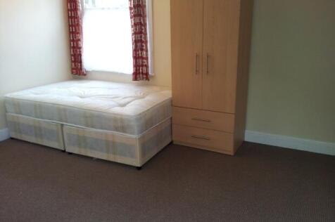 A simple, clean single bedroom featuring a bed ...