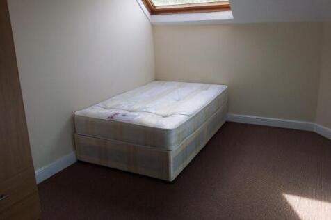 A bright single bedroom featuring a comfortable...